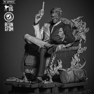 May include: A monochrome resin statue of Two-Face from DC Comics, seated in a detailed chair, holding a gun and a coin. The figure is split down the middle, with one side intact and the other scarred. The statue is on a wooden base with a duffel bag.