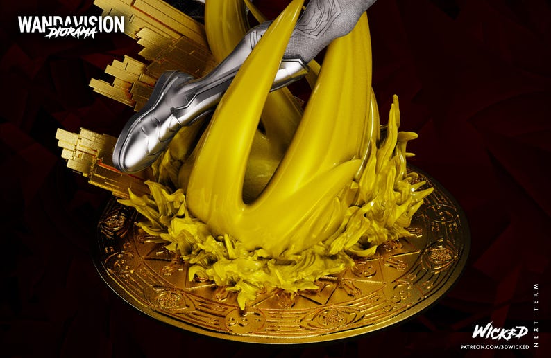 May include: A golden diorama base with a stylized yellow flame design and a silver figure's leg. The base has intricate patterns and the text "WANDAVISION DIORAMA" and "WICKED". The background is dark red.