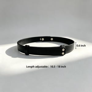 May include: A black belt featuring a smooth finish, silver-toned metal snap closures, and a sliding loop. The belt has a width of 0.6 inch and an adjustable length ranging from 10.5 to 18 inches, as indicated by the text printed on the image.
