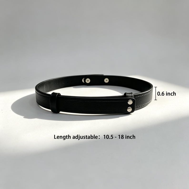 May include: A black belt featuring a smooth finish, silver-toned metal snap closures, and a sliding loop. The belt has a width of 0.6 inch and an adjustable length ranging from 10.5 to 18 inches, as indicated by the text printed on the image.