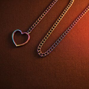 Puede incluir: Un collar con una cadena de eslabones tipo barbada y un colgante en forma de coraz&oacute;n. Tanto la cadena como el colgante presentan un acabado iridiscente de colores arco&iacute;ris que cambia entre tonos azules, morados, dorados y verdes.