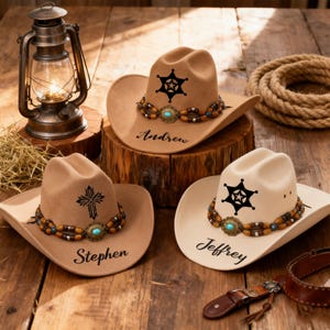 May include: Three cowboy hats in tan and cream colours, each with a sheriff's star or cross emblem. The hats have beaded hatbands with turquoise accents and personalized names: Andrew, Stephen, and Jeffrey. A vintage lantern and rope are in the background.