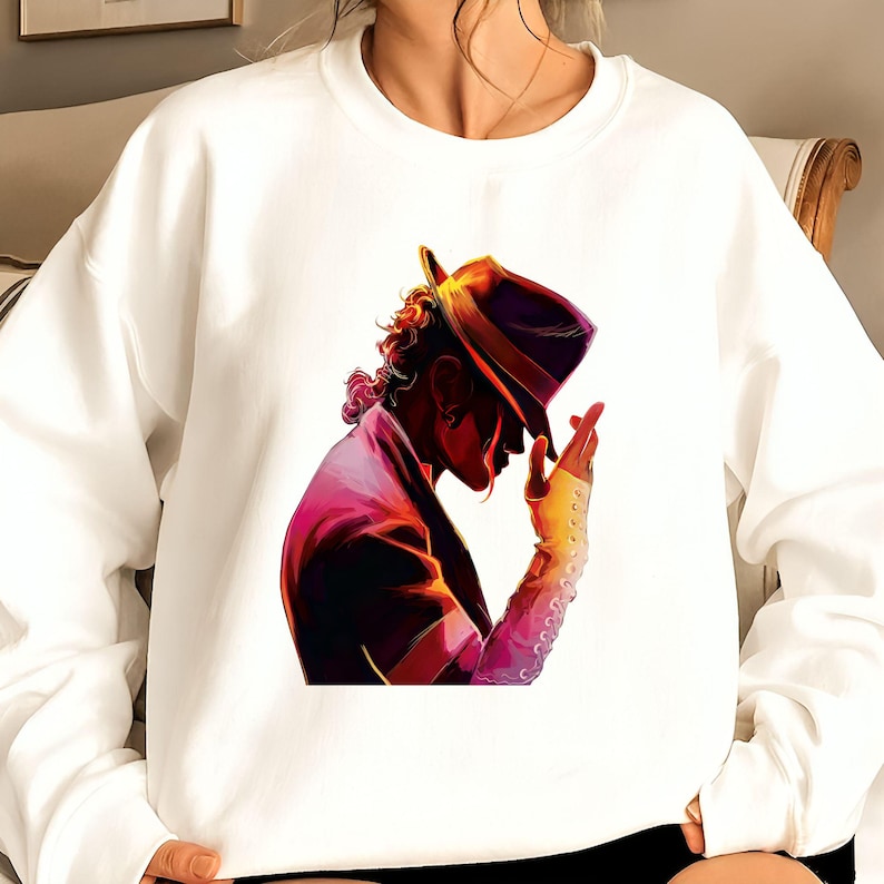 May include: White sweatshirt featuring a vibrant illustration of a person in a hat, with a purple jacket and a yellow glove. The artwork has a colorful, stylized design. The sweatshirt is a casual, comfortable garment.