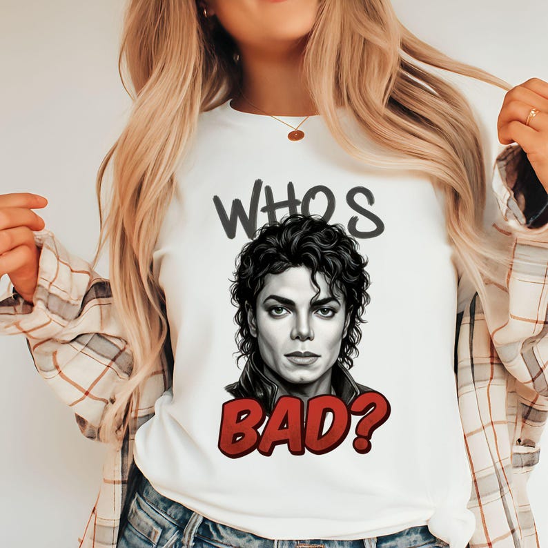 May include: White t-shirt featuring a portrait of Michael Jackson with the text "WHO'S BAD?" in black and red. The graphic tee has a crew neck and short sleeves. The shirt is made of a soft, comfortable material.
