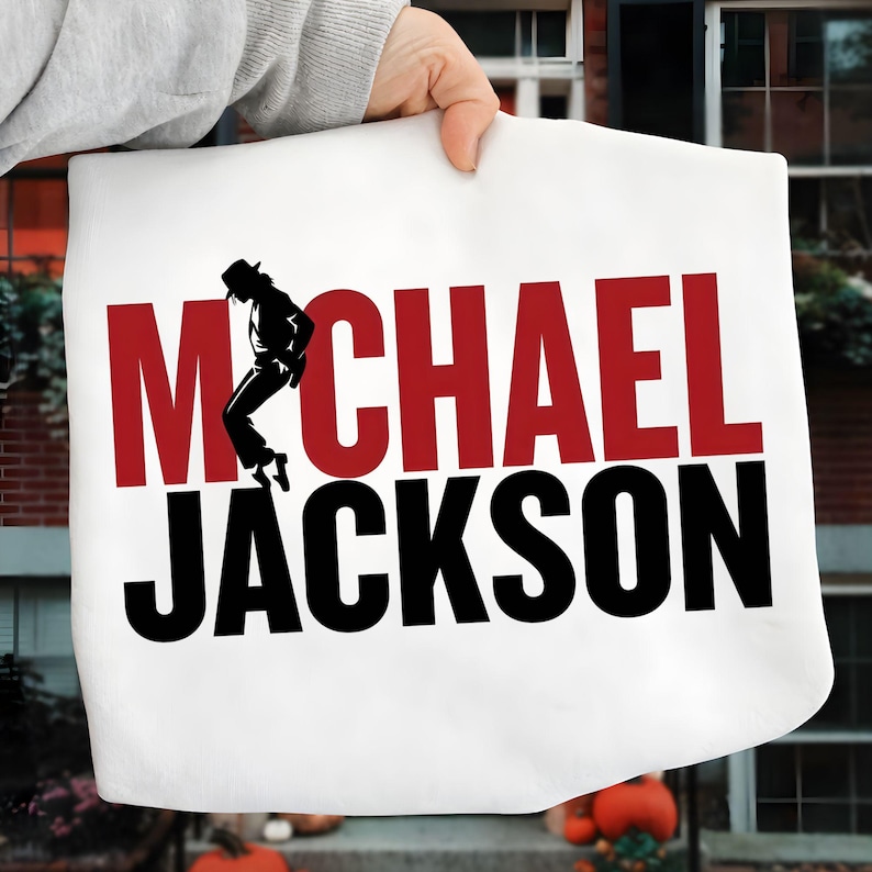 May include: White tote bag featuring the name "MICHAEL JACKSON" in large, bold letters. The word "MICHAEL" is in red, with a black silhouette of Michael Jackson performing a dance move. The word "JACKSON" is in black.