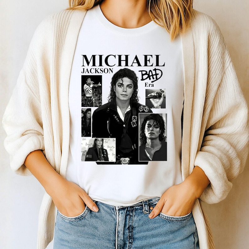May include: White t-shirt featuring a collage of black and white images of Michael Jackson. The shirt includes the text "MICHAEL JACKSON" above the word "BAD" and the word "Era".
