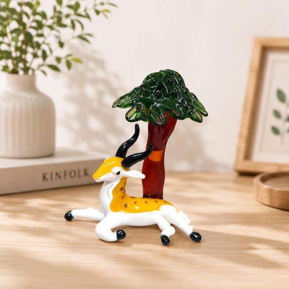A delicate hand-blown glass deer sheltering under a tree — the kind of micro-sculpture that stops visitors mid-sentence.