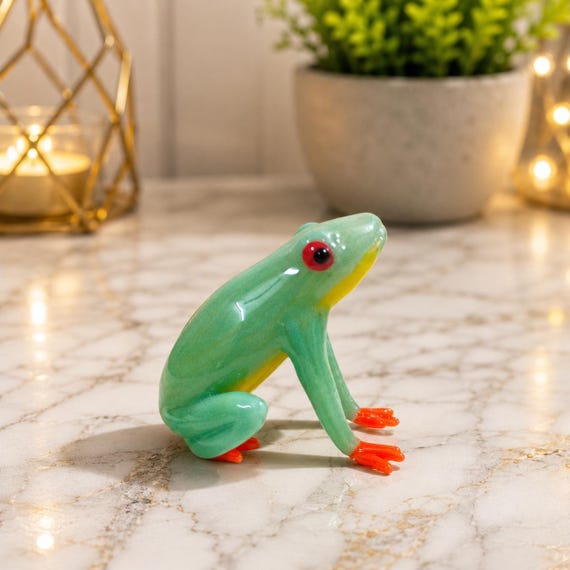 A breathtakingly detailed hand-blown glass red-eye tree frog sculpture — the kind of miniature art that stops guests mid-sentence.