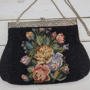 May include: Black beaded vintage handbag with a silver chain strap. The bag features a floral tapestry design in shades of pink, yellow, blue, and green. The top of the bag has a decorative silver frame.