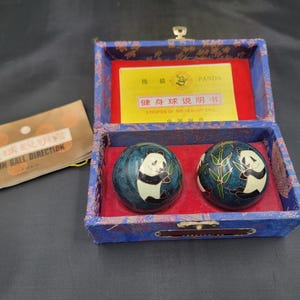 May include: Two dark blue spherical health balls featuring white and black panda illustrations and green bamboo stalks, housed in a rectangular blue fabric-covered box with a red interior lining and a yellow instructional card with text.