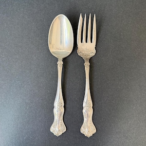 May include: A white ceramic mug with a black handle and the text "But First, Coffee" in a black, bold font. The mug is sitting on a wooden surface. The mug is approximately 4 inches tall.