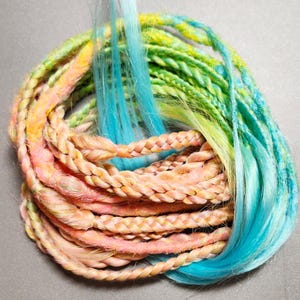 May include: A bundle of colorful synthetic hair extensions in shades of pink, yellow, green, and blue. The hair is braided and twisted, with some strands hanging loose. The overall effect is vibrant and eye-catching, suitable for creating bold hairstyles.