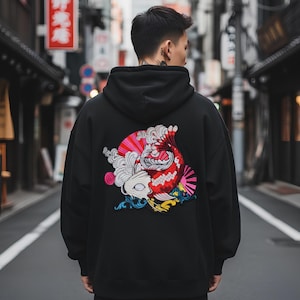 Könnte beinhalten: Schwarzer Kapuzenpullover mit einem großen, farbenfrohen, gestickten Koi-Karpfen-Design auf dem Rücken. Der Koi-Karpfen hat rote, weiße, rosa und blaue Akzente. Der Hoodie hat eine Kapuze und lange Ärmel.