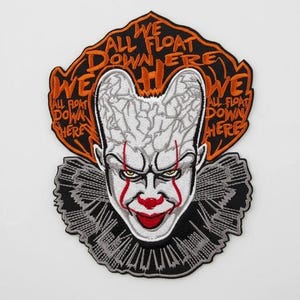 May include: Embroidered patch depicting a scary clown face with red details and the text "WE ALL FLOAT DOWN HERE" in orange. The patch has a black and white ruffled collar, suitable for clothing or accessories.