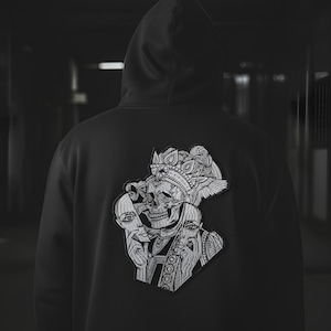 May include: Black hooded sweatshirt with a detailed black and white graphic on the back. The graphic features a skull wearing a crown, holding a mask, and surrounded by two faces. The design is intricate and artistic.