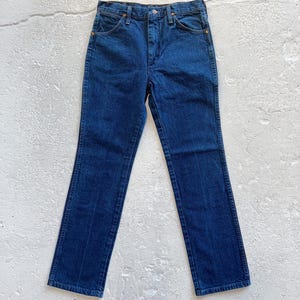 Pu&ograve; includere: Un paio di jeans in denim blu scuro con gamba dritta. I jeans hanno vita alta e chiusura con bottone.