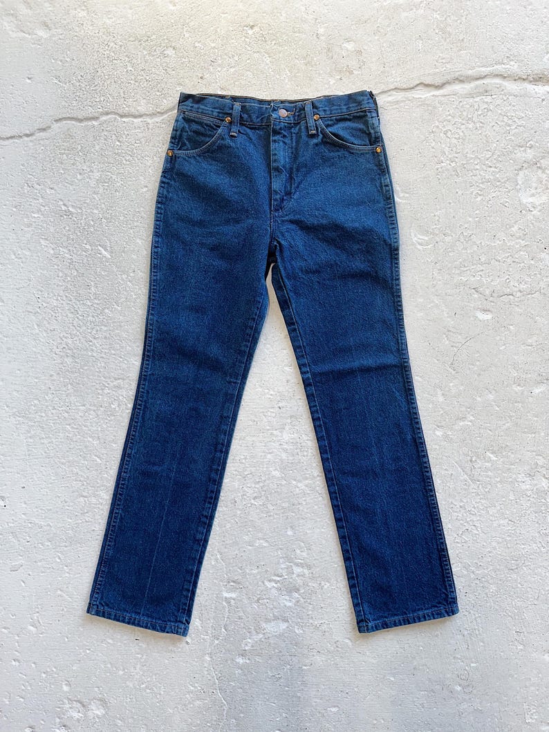 Pu&ograve; includere: Un paio di jeans in denim blu scuro con gamba dritta. I jeans hanno vita alta e chiusura con bottone.