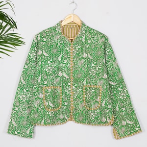 May include: A long-sleeve quilted jacket in a vibrant green hue featuring a white floral and botanical print. The jacket has a round neckline, a front button closure, and two patch pockets on the front, all finished with a striped trim.