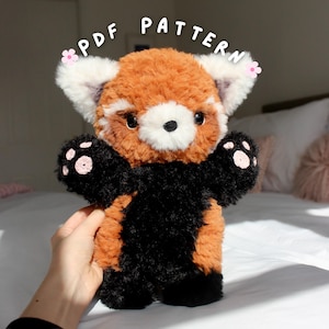 Könnte beinhalten: Ein Stofftier-Rotfuchs mit einem flauschigen orange-schwarzen Körper, weißem Gesicht und rosa Pfoten. Der Text "PDF PATTERN" steht über dem Stofftier.