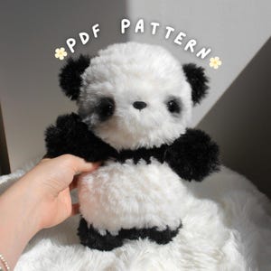 May include: A plush panda bear with black and white fur. The panda has black ears, paws, and a collar. The text "PDF PATTERN" is written above the panda.