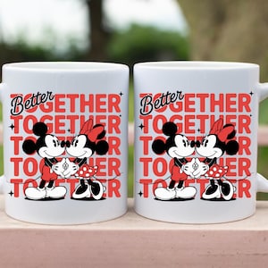 Op de afbeelding: Twee witte keramische mokken met de woorden "Better Together" in rood en zwart. Elke mok heeft een afbeelding van Mickey en Minnie Mouse die elkaar omarmen. Perfect voor koppels of Disney-fans.