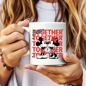 Op de afbeelding: Witte keramische mok met Mickey en Minnie Mouse die elkaar omarmen. De mok toont de woorden "Better Together" in rood en zwart, met de afbeeldingen van de personages. Een leuk cadeau voor koppels.
