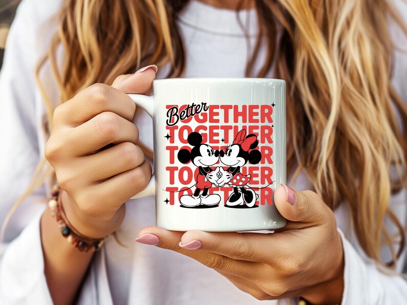 Op de afbeelding: Witte keramische mok met Mickey en Minnie Mouse die elkaar omarmen. De mok toont de woorden "Better Together" in rood en zwart, met de afbeeldingen van de personages. Een leuk cadeau voor koppels.