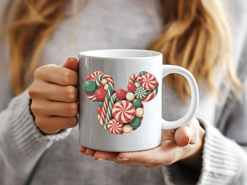 Puede incluir: Taza de cer&aacute;mica blanca con un dise&ntilde;o festivo de una cabeza de Mickey Mouse hecha de caramelos. El dise&ntilde;o incluye bastones de caramelo a rayas rojas y blancas, caramelos redondos verdes y rojos y caramelos en espiral rojos y blancos.