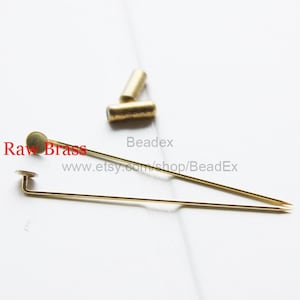 Puede incluir: Dos alfileres de metal dorado con cabeza redonda y una aguja recta. Los alfileres están sobre una superficie blanca. El texto "Raw Brass" es visible en la imagen. El texto "Beadex" y "www.etsy.com/shop/BeadEx" también son visibles en la imagen.