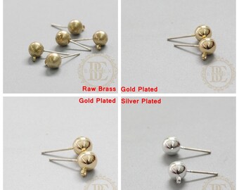 May include: Four pairs of earring findings in different finishes: raw brass, gold plated, gold plated, and silver plated. Each finding features a small round ball at the end of a straight post.