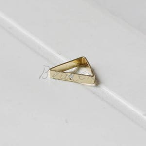 May include: Gold triangle jump ring with a small hole in the center.