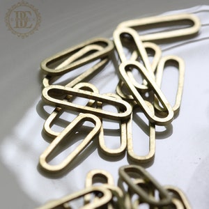 May include: A pile of gold-coloured metal rings, each with a slightly oval shape. The rings are linked together, creating a chain-like effect.