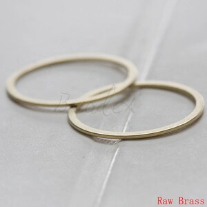 May include: Two raw brass rings, one slightly larger than the other, are stacked on top of each other. The rings are smooth and have a slightly rounded edge.