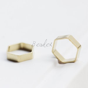 May include: Two gold-coloured metal hexagonal rings. The rings are open and have a smooth, polished finish.