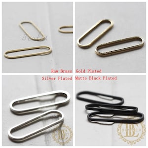 Puede incluir: Cuatro anillos metálicos ovalados en diferentes acabados: latón en bruto, chapado en oro, chapado en plata y negro mate. Los anillos miden aproximadamente 2,5 cm de largo.