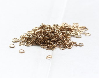 Puede incluir: Un montón grande de pequeños anillos de salto de color dorado. Los anillos están hechos de latón en bruto y son perfectos para la fabricación de joyas.