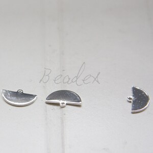 May include: Three silver metal half-circle charms with a small hole at the top for attaching to jewelry or other crafts.