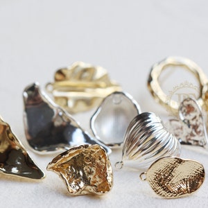 Könnte beinhalten: Sortiment an goldenen und silbernen Metall-Schmuckfunden, darunter ein Herz, ein Kreis und verschiedene unregelmäßige Formen.