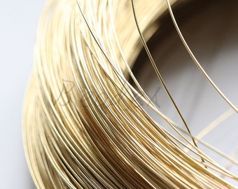 Pode incluir: Close-up de uma bobina de fio dourado. O fio é enrolado firmemente, criando uma aparência densa e texturizada. O brilho metálico do fio sugere que é feito de um metal precioso, adequado para a fabricação de joias ou outros projetos de artesanato.