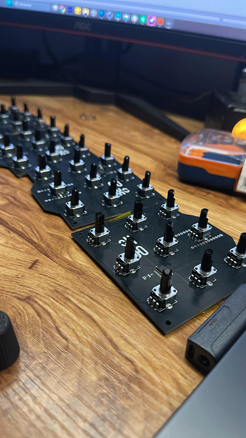 Op de afbeelding: Close-up van zwarte printplaten met talrijke kleine, zwarte knoppen en zilveren componenten. De platen zijn gerangschikt op een houten oppervlak, met een paar andere items zichtbaar op de achtergrond.