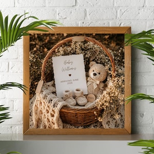 Rustic baby announcement basket featuring a plush teddy bear, cream knit booties, baby's breath flowers, and a card reading "Baby Williams Arriving June 2026" on a beige macrame blanket.