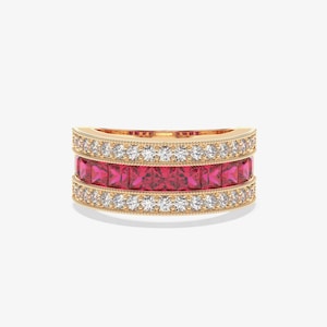 May include: A gold band ring with three rows of gemstones. The top and bottom rows feature small, clear stones, while the center row showcases square-cut, vibrant pink gemstones. The ring has a detailed, textured design.