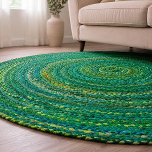 Può includere: Un tappeto rotondo intrecciato caratterizzato da un mix vivace di fibre verdi, verde acqua e gialle. Il tappeto è realizzato con un motivo circolare concentrico, che mette in risalto una superficie strutturata di fili intrecciati.