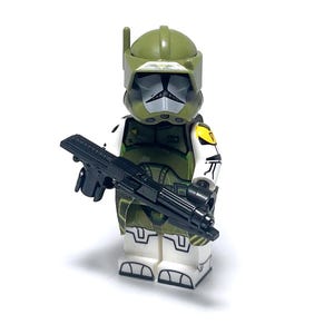 May include: A green and white minifigure with a black weapon. The minifigure has a helmet and armor with yellow accents. The figure is holding a black rifle. The background is white.