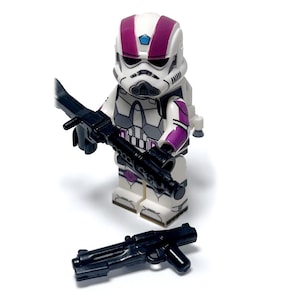 Può includere: Minifigure Lego Star Wars bianca e viola con un fucile blaster nero. Il casco ha dettagli viola. Un secondo fucile blaster nero è a terra. Oggetto da collezione.