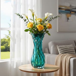 Pode incluir: Um vaso alto de vidro turquesa com um design em espiral, cheio de rosas amarelas, callas brancas e vegetação. O vaso está sobre uma mesa redonda de madeira. As flores estão em plena floração. O vaso tem cerca de 30 cm de altura.