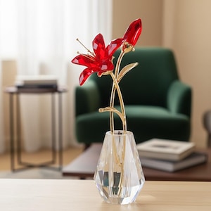 Op de afbeelding: Een decoratief kristallen bloemstuk met een felrode bloem en knop met goudkleurige stelen en bladeren. De bloem staat in een heldere, facetgeslepen kristallen vaas, wat een luxe woondecoratie accent creëert.