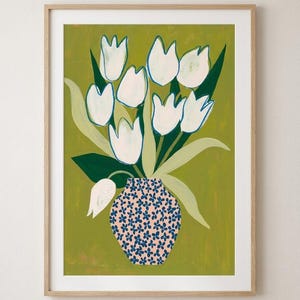 Pode incluir: Uma impressão artística emoldurada apresentando um buquê de tulipas brancas com contornos azuis sobre um fundo verde-oliva sólido. As flores estão dispostas em um vaso rosa claro decorado com um padrão repetitivo de pequenas flores azul-escuras.