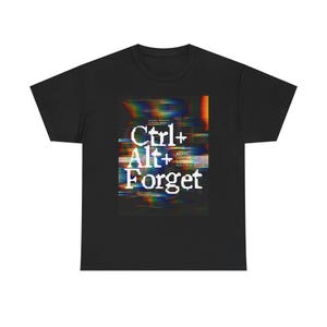 Puede incluir: Camiseta negra con un diseño gráfico blanco "Ctrl+Alt+Forget", apilado verticalmente. El diseño tiene un efecto de fallo con líneas horizontales de colores. La camiseta es de cuello redondo clásico.