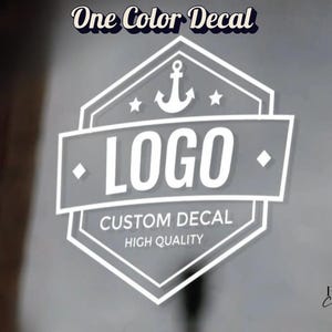 May include: A white vinyl decal featuring a hexagonal emblem with an anchor icon at the top, the word LOGO in the center, and the text CUSTOM DECAL and HIGH QUALITY below. The words One Color Decal appear at the top and Print chic at the bottom.